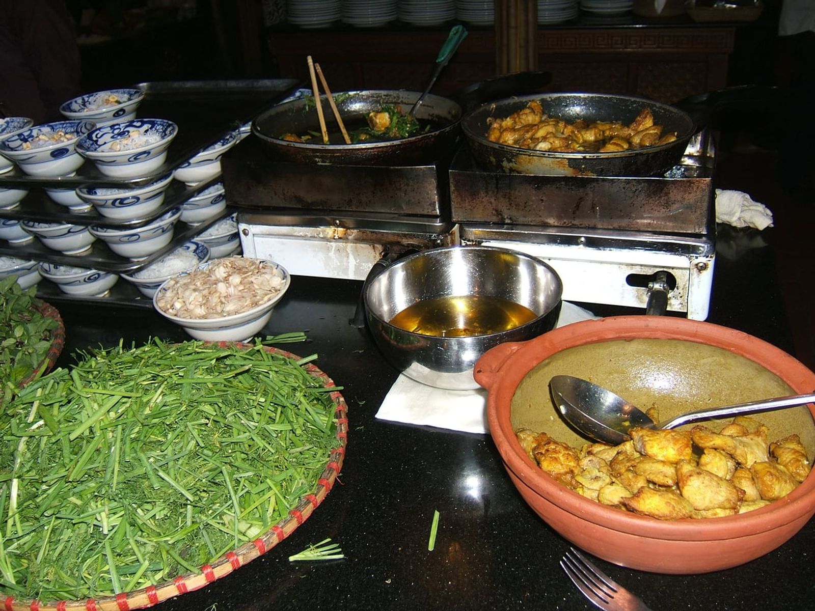 チャーカーの材料（焼いた魚・ディル・青ネギ）と卓上コンロ · 写真: Viethavvh at vi.wikipedia / Public domain (Wikimedia Commons)